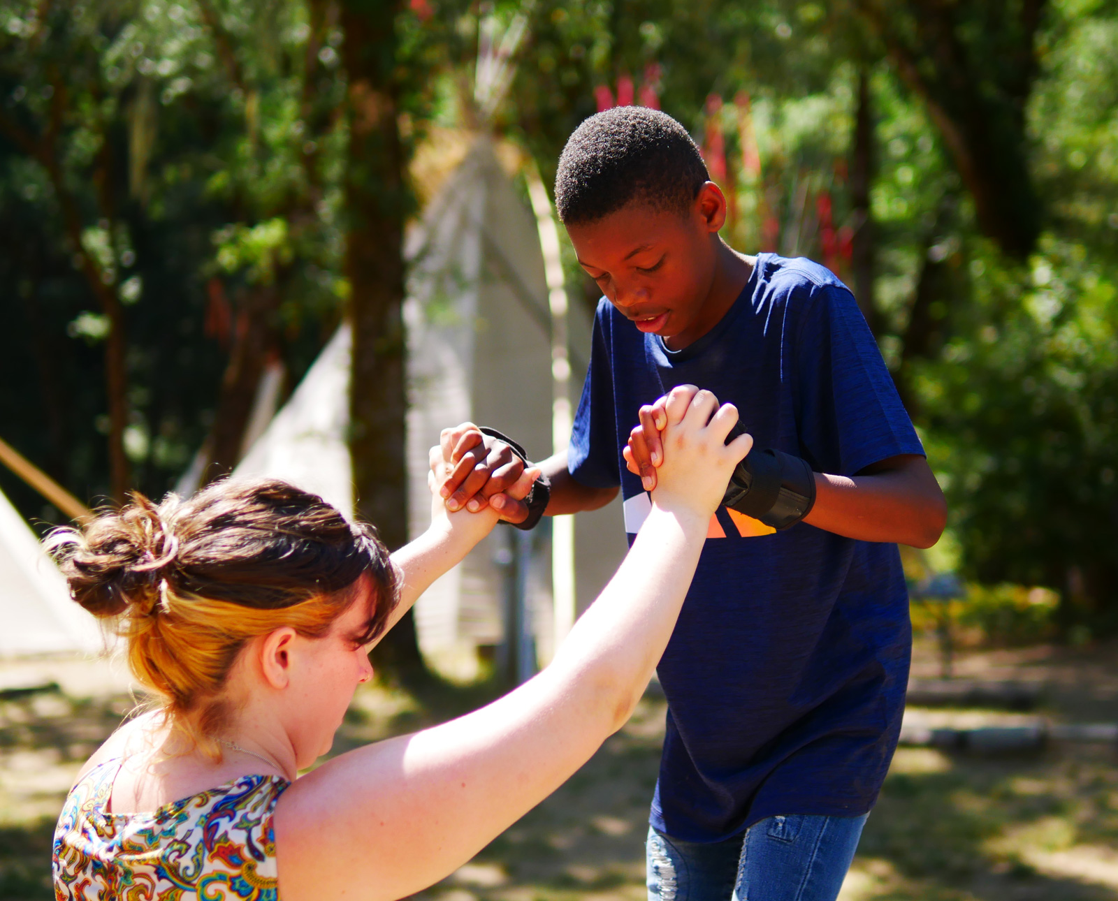 A camper on stilts being supported by a staff member